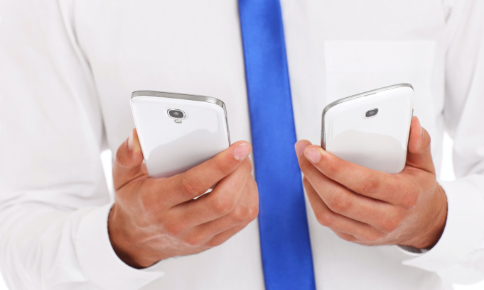 Midsection of businessman with two smarphones