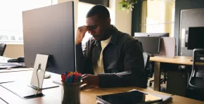 Stressed black businessman sat at office desk with mental illness