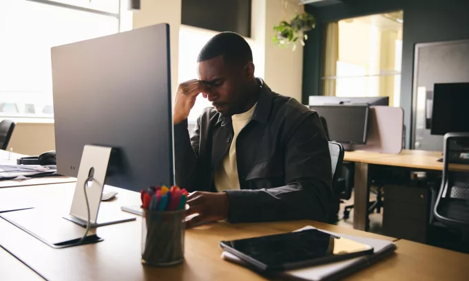 Stressed black businessman sat at office desk with mental illness