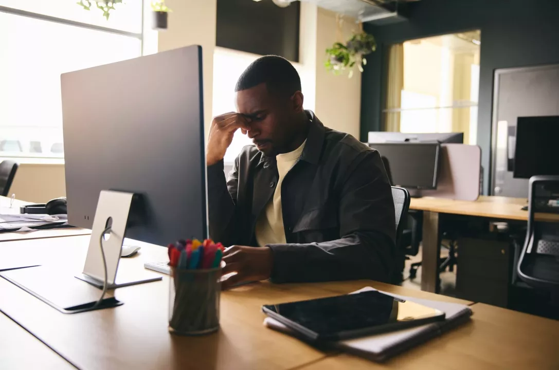 Stressed black businessman sat at office desk with mental illness