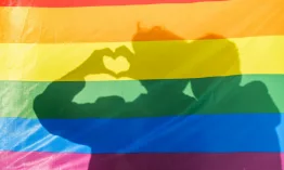 Two shadows of young people behind an lgtbi flag